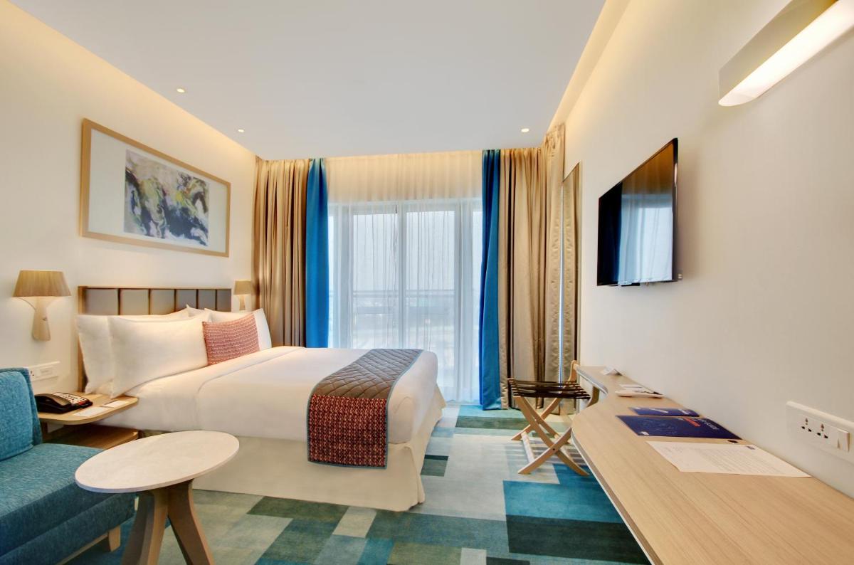 a hotel room with a bed and a couch at Holiday Inn Bengaluru Racecourse by IHG in Bengaluru a hotel room with a bed and a couch at Holiday Inn Bengaluru Racecourse by IHG in Bengaluru