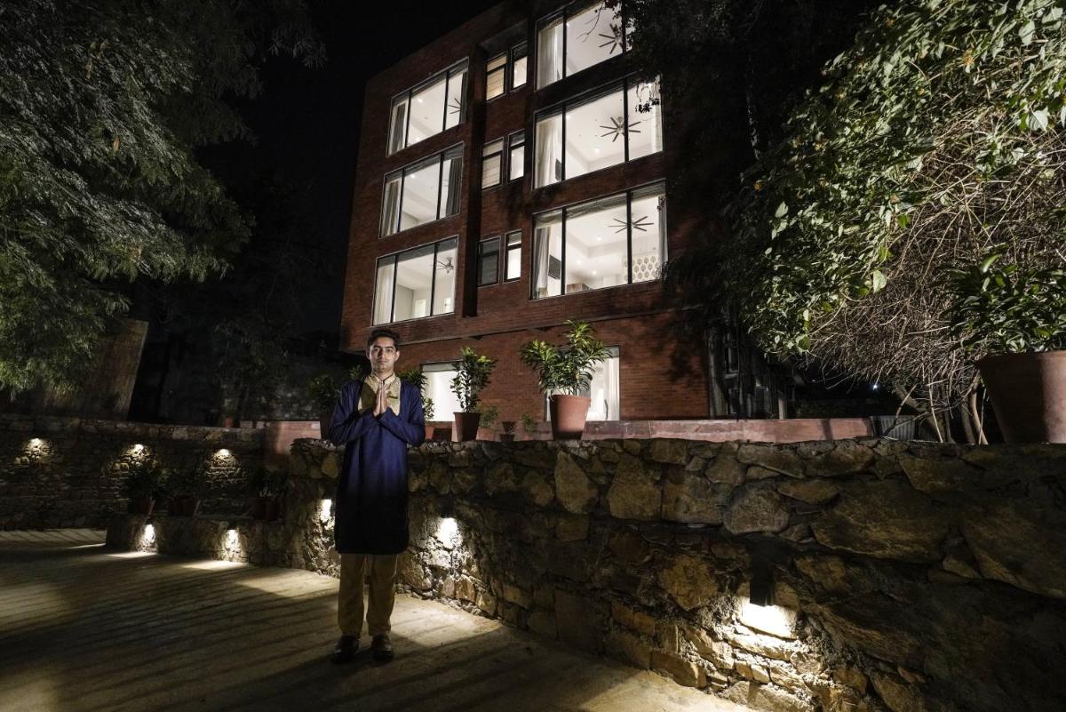 a woman standing in front of a building at night at Brij Nest, Jaipur - An All Suite Boutique Hotel in Jaipur