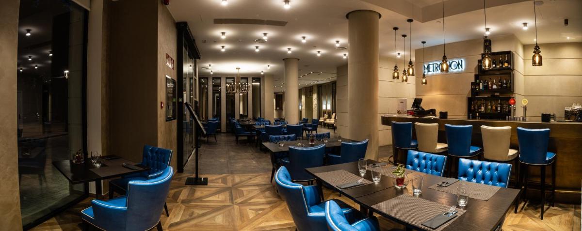 Un restaurante con sillas y mesas azules y un bar. en Boutique Hotel Élke Spa Superior, en Sant Feliu de Guíxols