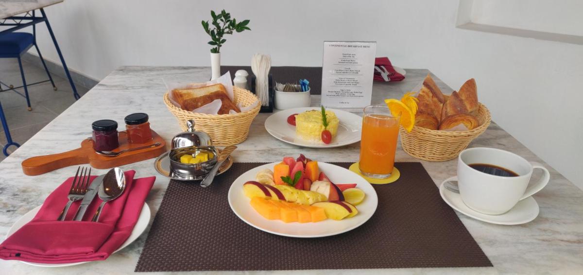 a table with two plates of fruit and cups of coffee at Grand Hotel D'Europe in Puducherry