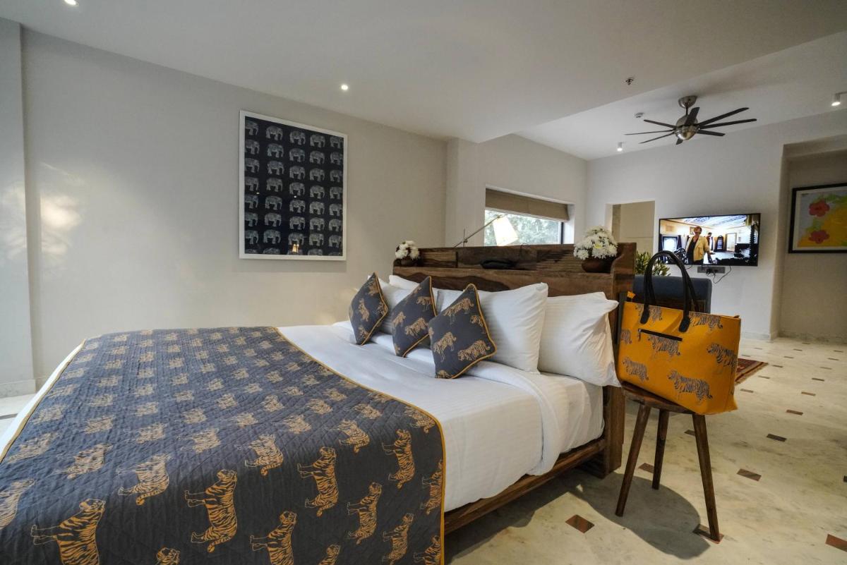 a bedroom with a large bed with blue and yellow pillows at Brij Nest, Jaipur - An All Suite Boutique Hotel in Jaipur