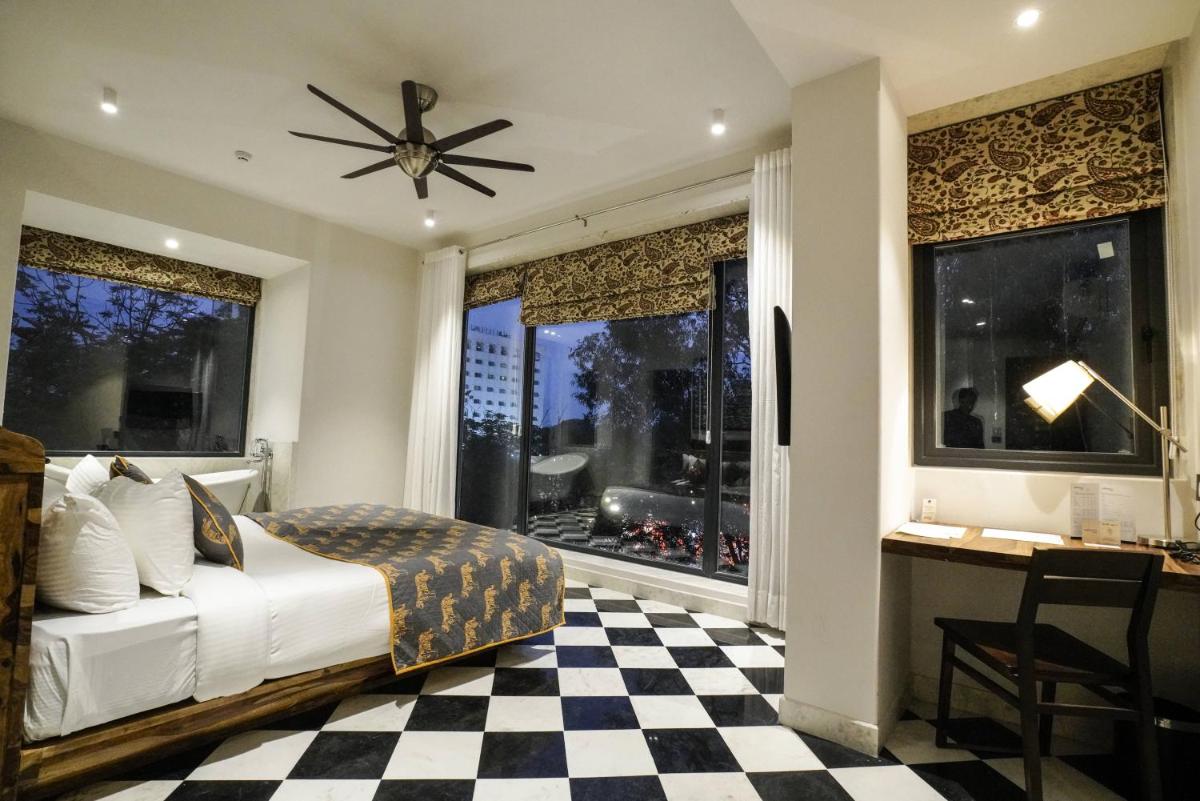 a bedroom with a bed and a desk and windows at Brij Nest, Jaipur - An All Suite Boutique Hotel in Jaipur