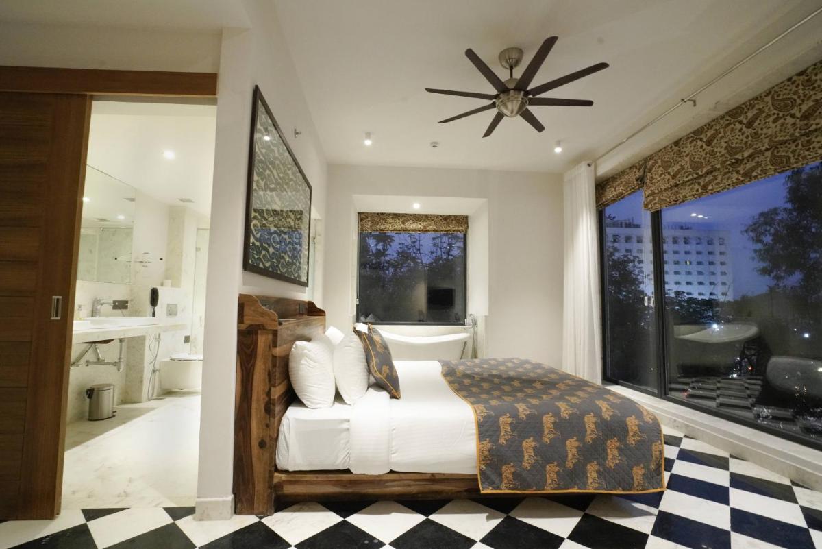 a bedroom with a bed and a large window at Brij Nest, Jaipur - An All Suite Boutique Hotel in Jaipur