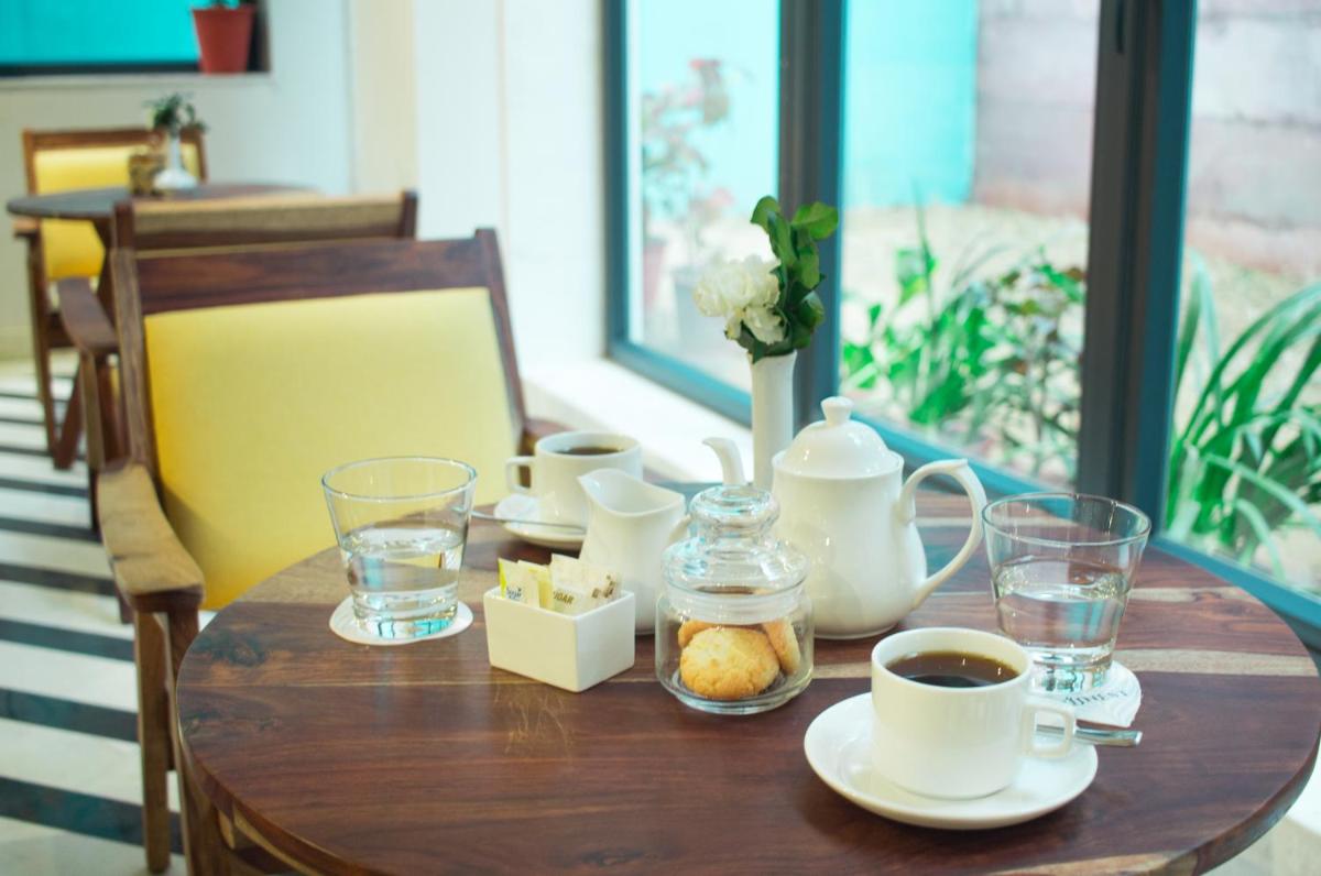 a wooden table with a cup of coffee and tea at Brij Nest, Jaipur - An All Suite Boutique Hotel in Jaipur
