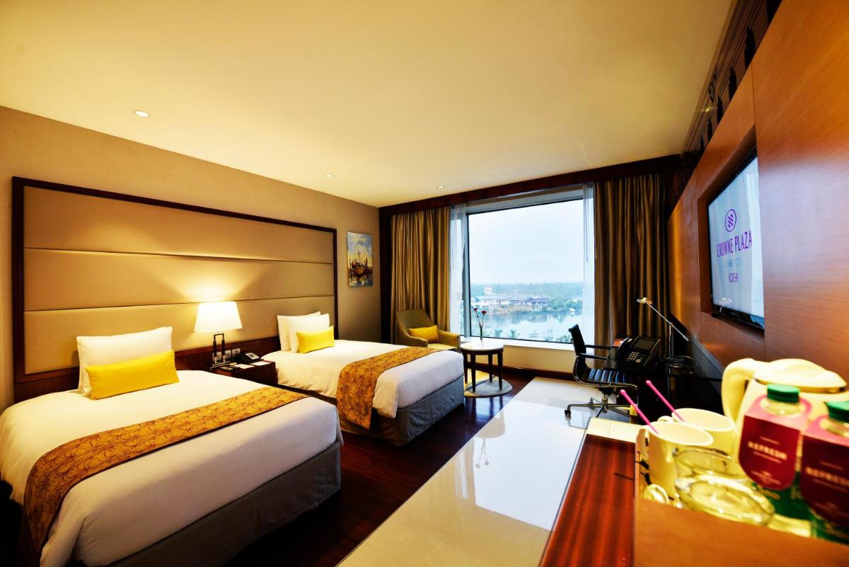 a hotel room with two beds and a large window at Crowne Plaza Kochi by IHG in Cochin