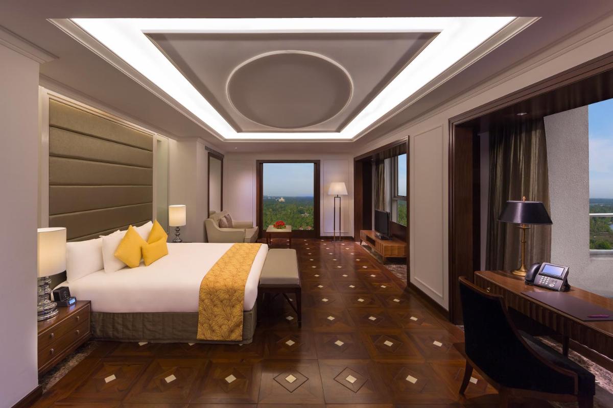 a hotel room with a bed and a desk and window at Crowne Plaza Kochi by IHG in Cochin