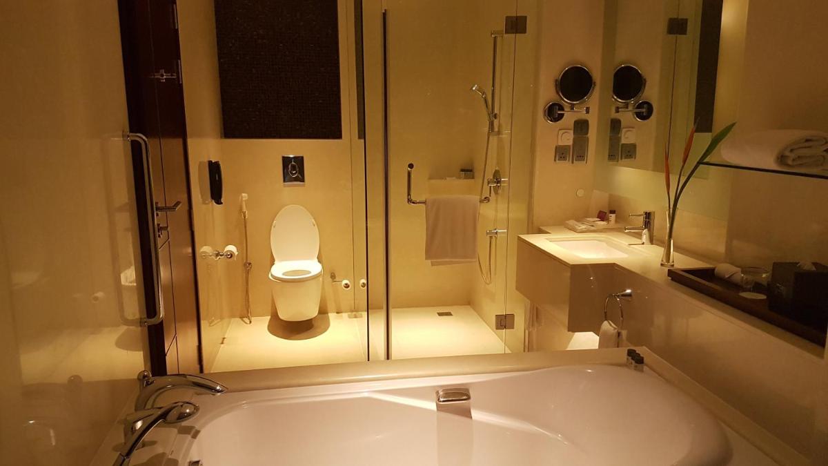 a bathroom with a tub and a toilet and a sink at Crowne Plaza Kochi by IHG in Cochin