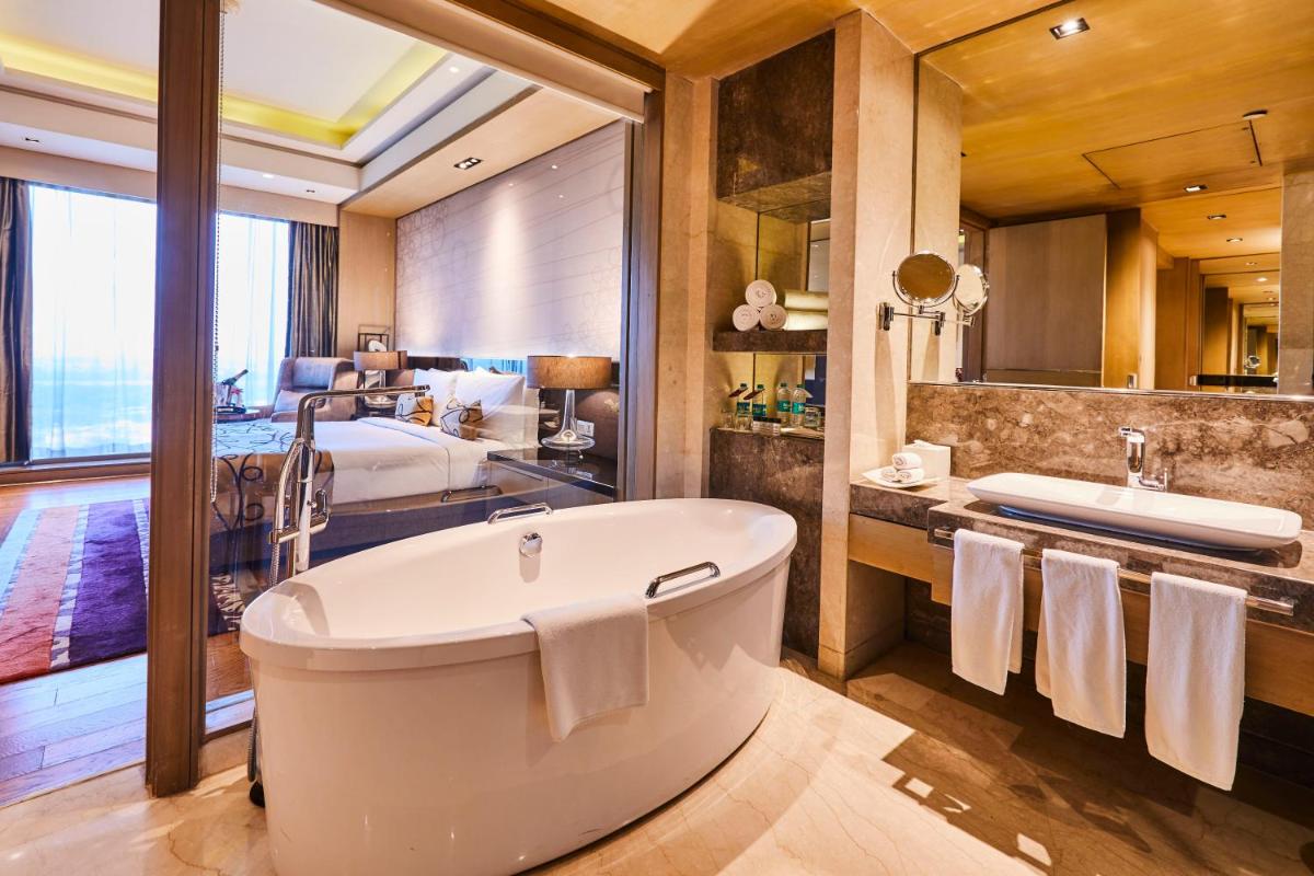 a bathroom with a large tub and a bedroom at Crowne Plaza New Delhi Rohini by IHG in New Delhi a bathroom with a large tub and a bedroom at Crowne Plaza New Delhi Rohini by IHG in New Delhi