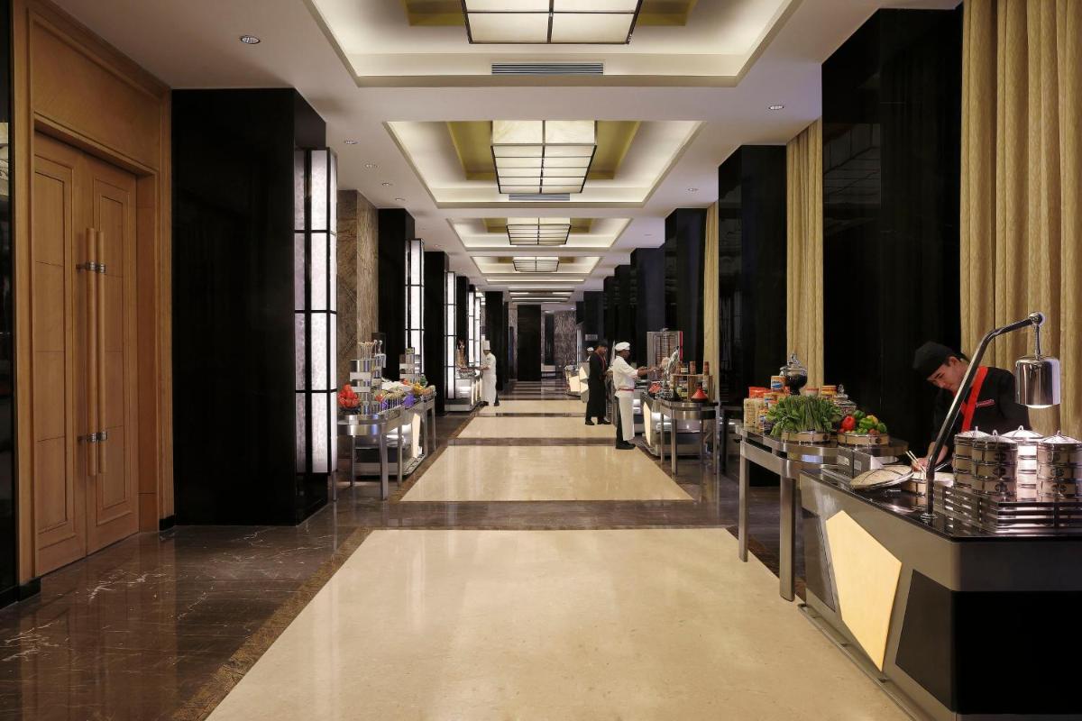 a hallway in a building with people walking down it at InterContinental Jaipur Tonk Road by IHG in Jaipur