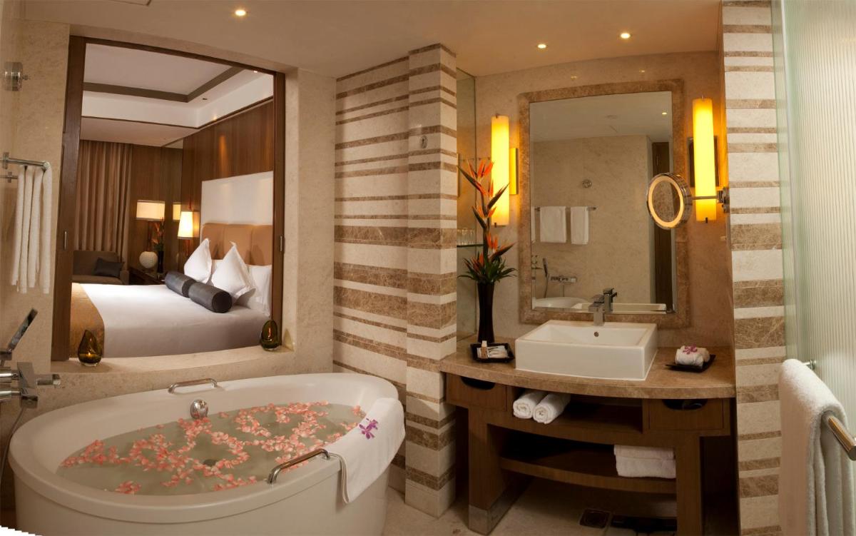 a bathroom with a tub and a bedroom with a bed at Crowne Plaza New Delhi Okhla by IHG in New Delhi