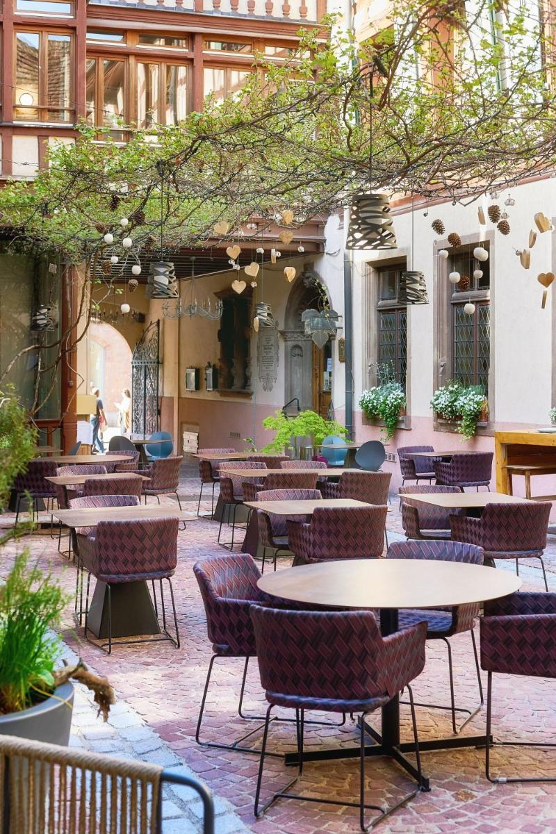 un patio avec tables et chaises dans un bâtiment dans l'établissement Relais & Châteaux La Maison Des Têtes, à Colmar 37 autres photos