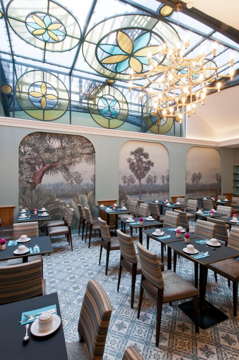 une salle à manger avec des tables et des chaises et un plafond en vitraux dans l'établissement Hôtel Saint-Pétersbourg Opéra & Spa, à Paris 73 autres photos