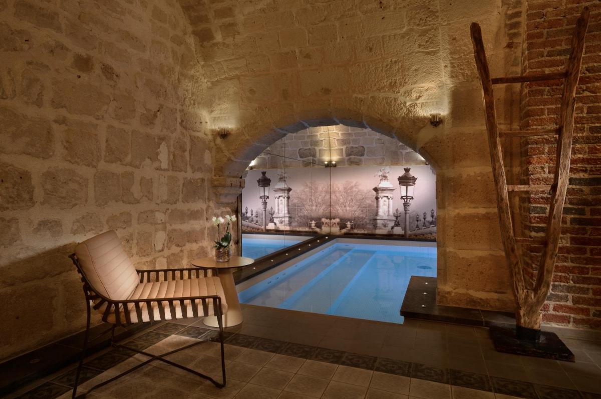 une piscine dans un bâtiment avec un mur en briques dans l'établissement Hotel La Lanterne & Spa By Timhotel, à Paris