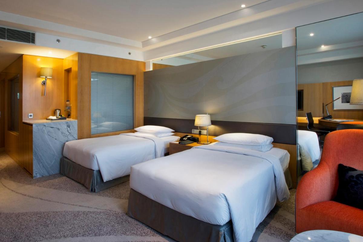 a hotel room with two beds and a chair at Hyatt Regency Gurgaon in Gurgaon