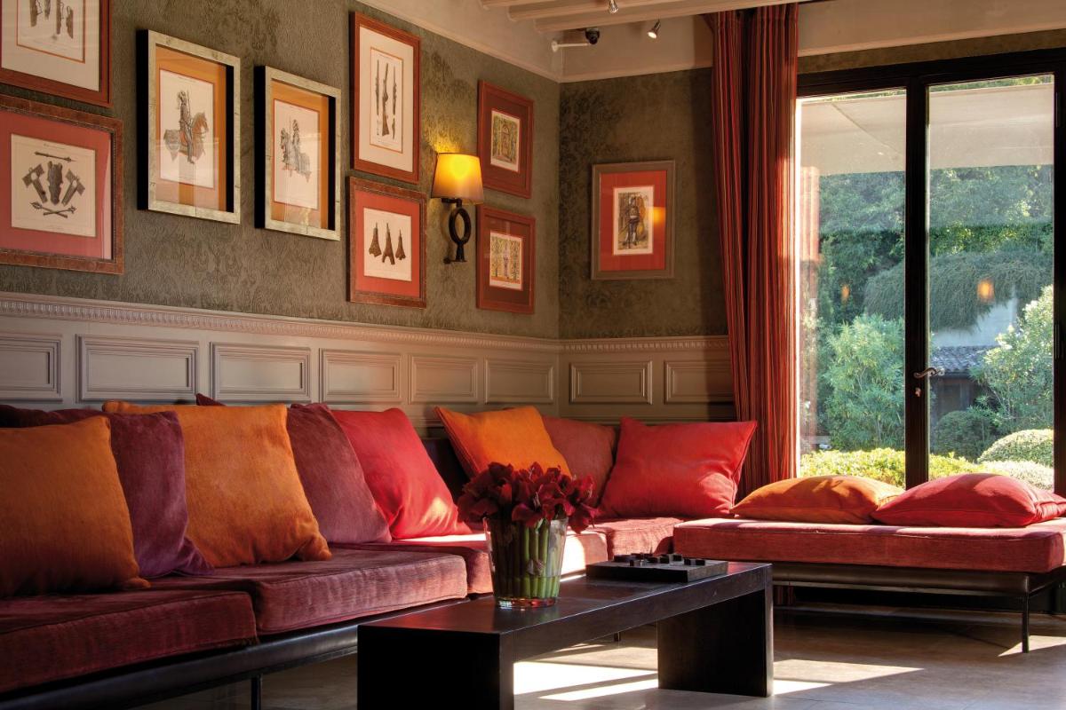 un salon avec un canapé rouge et une table dans l'établissement Hôtel du Château & Spa - Teritoria, à Carcassonne