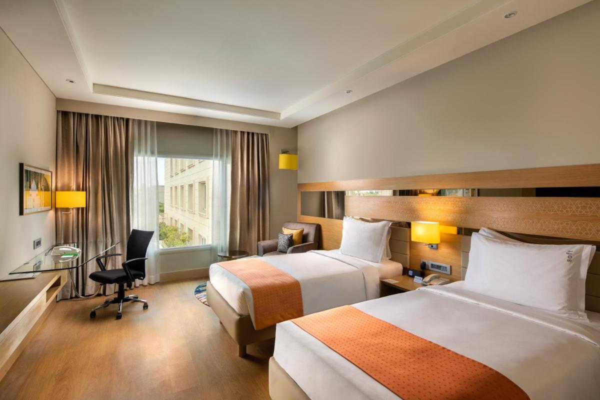 a hotel room with two beds and a desk at Holiday Inn Agra MG Road an IHG Hotel in Agra