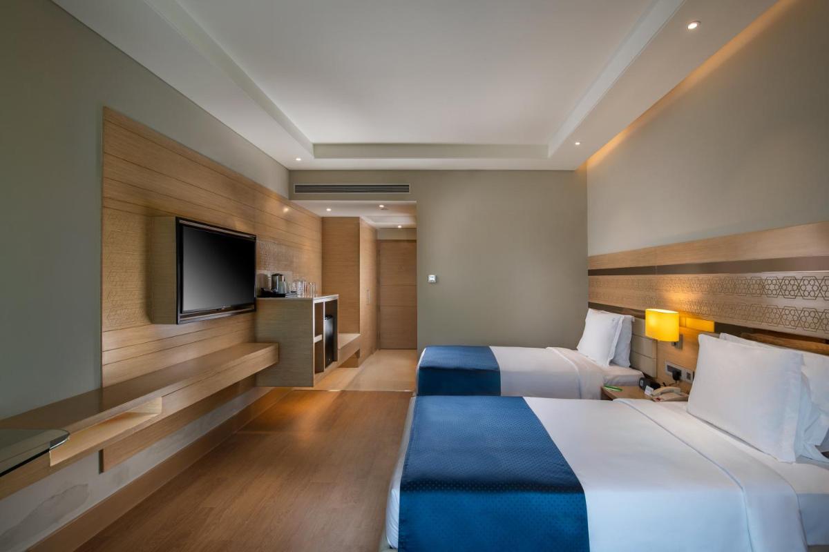 a hotel room with two beds and a flat screen tv at Holiday Inn Agra MG Road an IHG Hotel in Agra