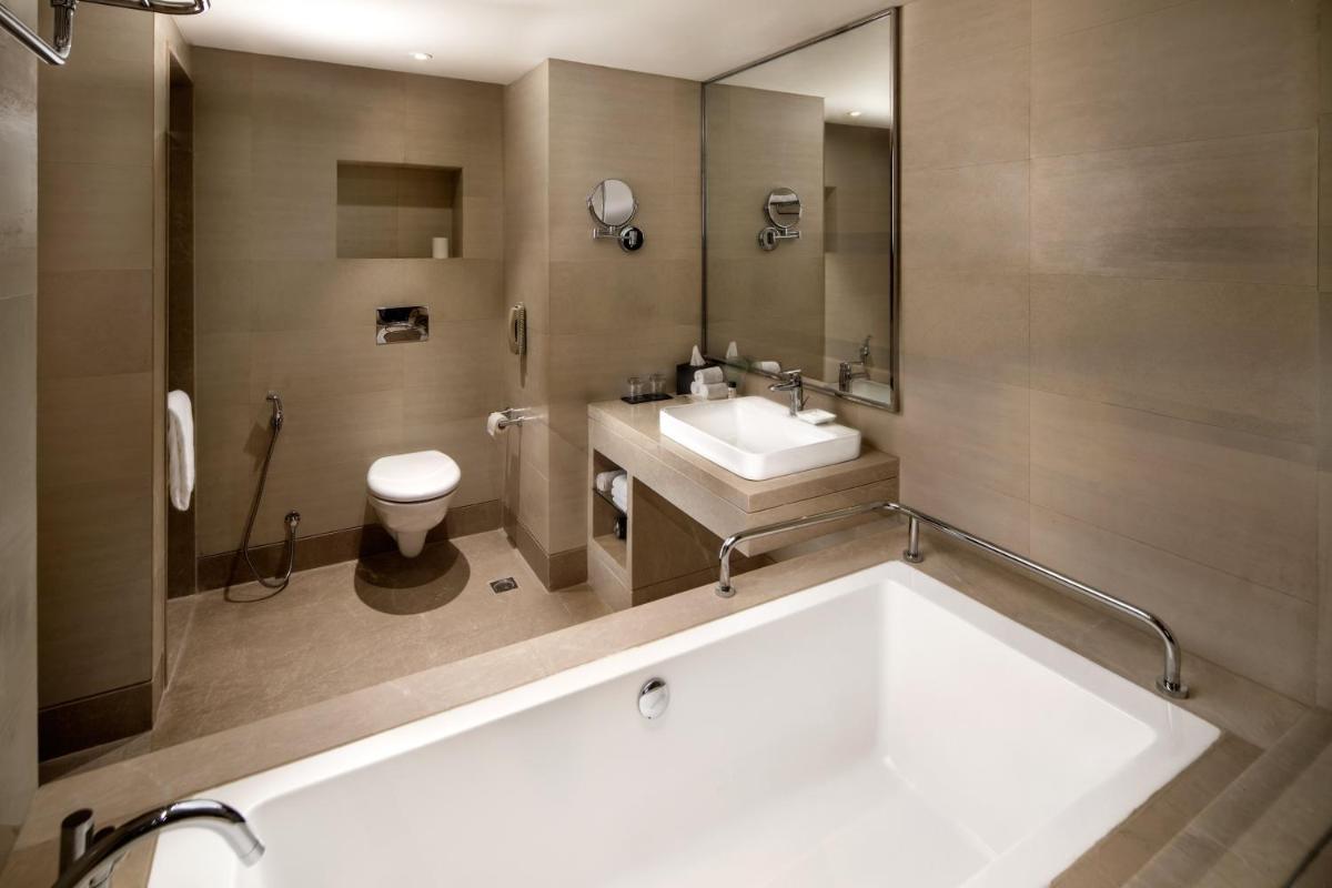 a bathroom with a tub and a sink and a toilet at Holiday Inn Agra MG Road an IHG Hotel in Agra