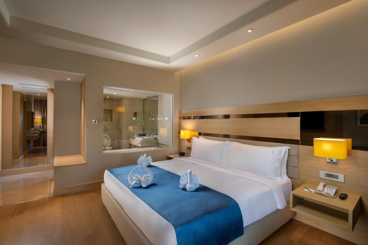 a bedroom with a large white bed with blue sheets at Holiday Inn Agra MG Road an IHG Hotel in Agra