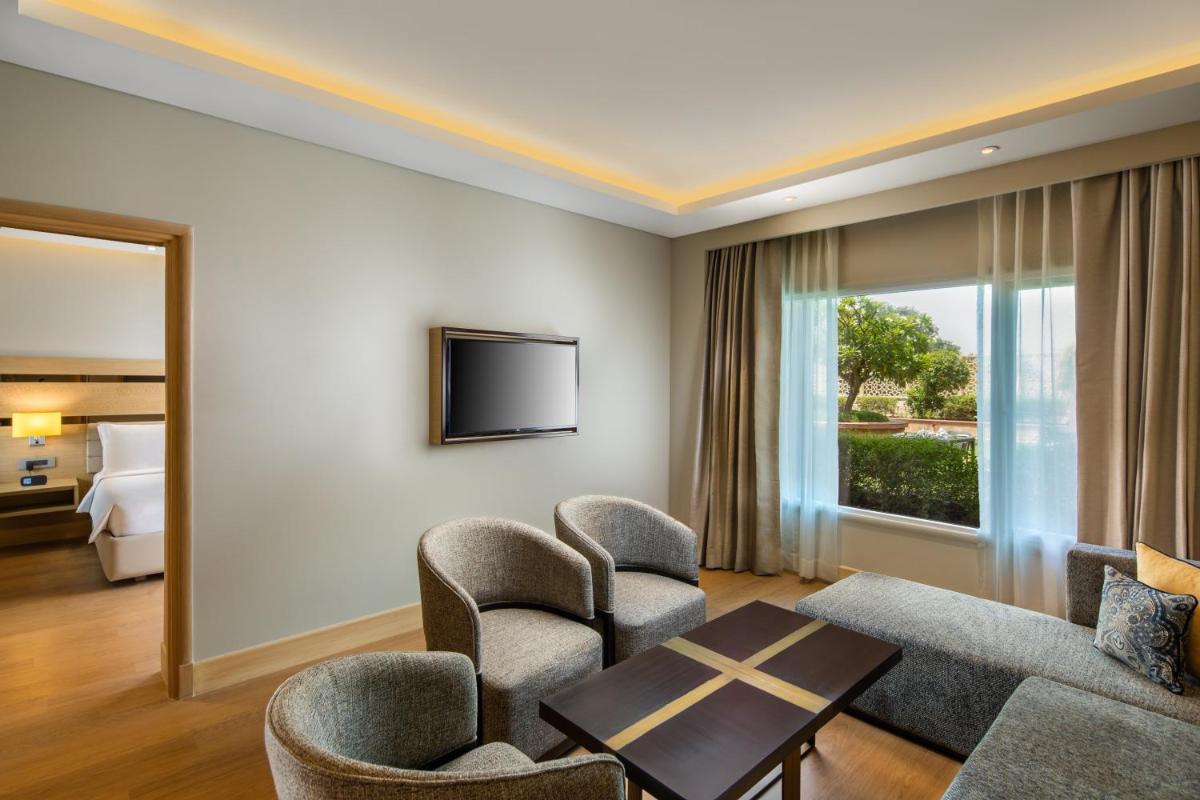 a living room with chairs and a table and a tv at Holiday Inn Agra MG Road an IHG Hotel in Agra