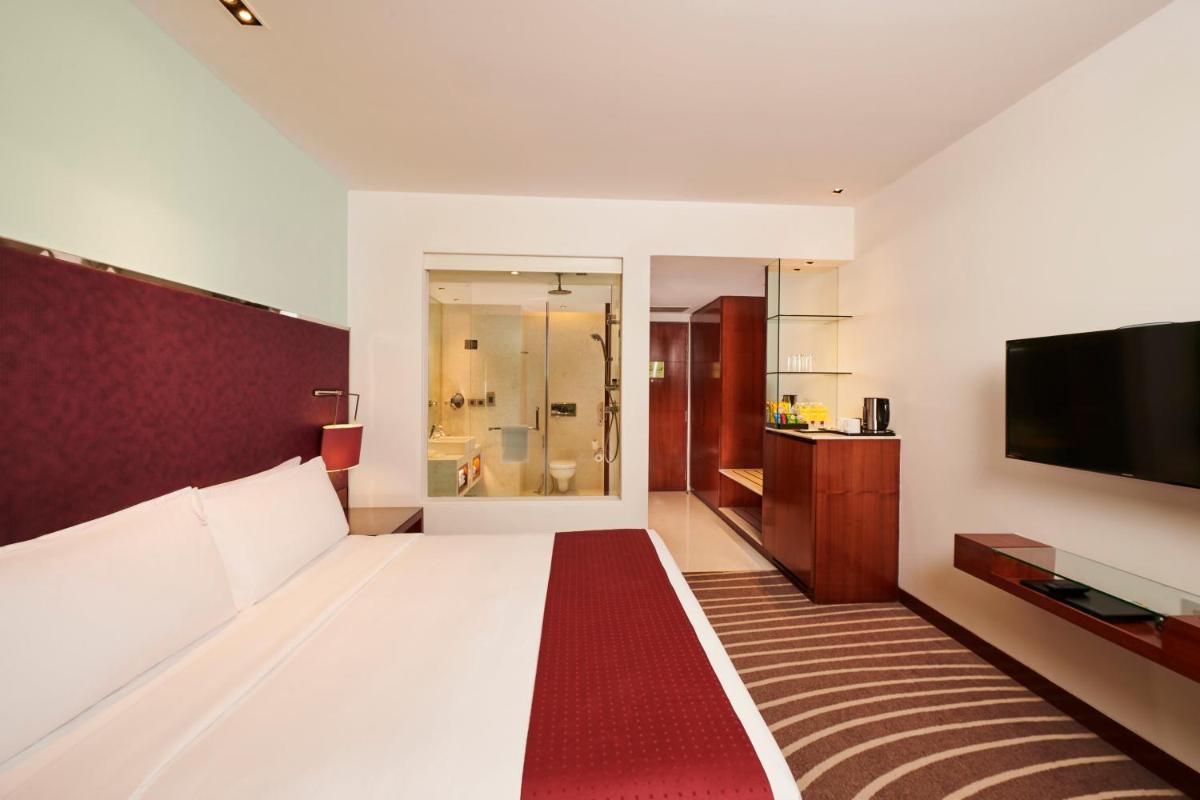 a hotel room with a bed and a flat screen tv at Holiday Inn Mumbai International Airport by IHG in Mumbai