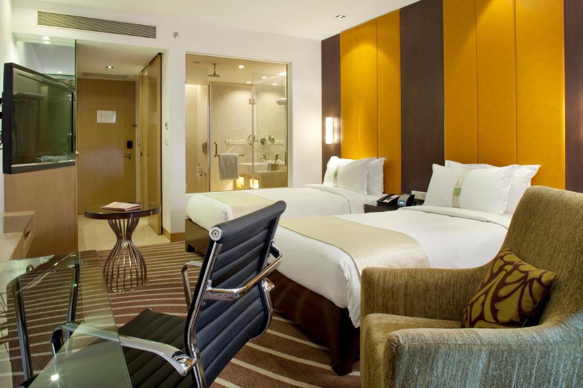 a hotel room with two beds and two chairs at Holiday Inn Mumbai International Airport by IHG in Mumbai