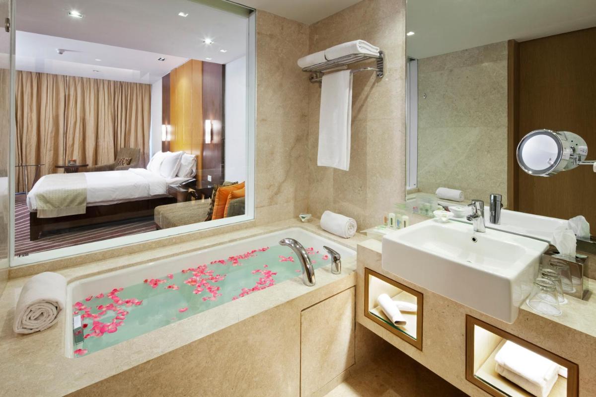 a bathroom with a sink and a tub with a mirror at Holiday Inn Mumbai International Airport by IHG in Mumbai