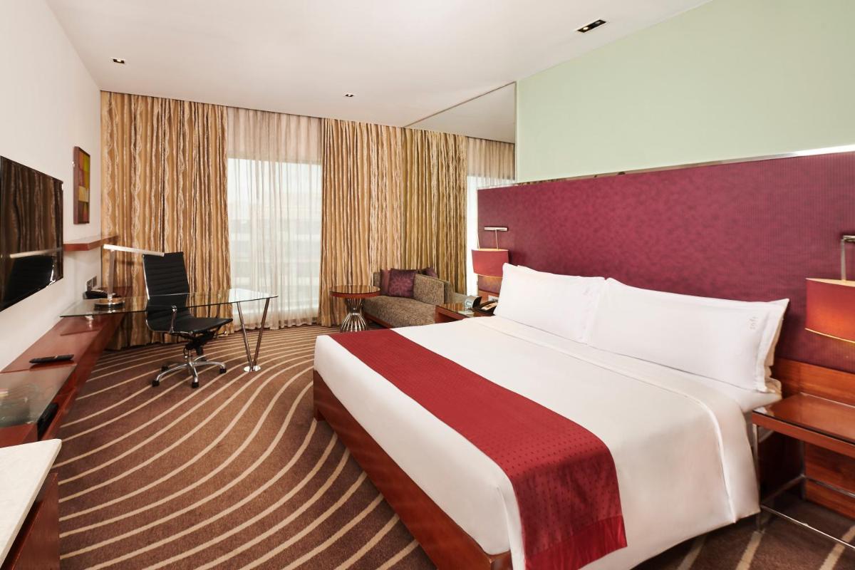 a hotel room with a large bed and a desk at Holiday Inn Mumbai International Airport by IHG in Mumbai