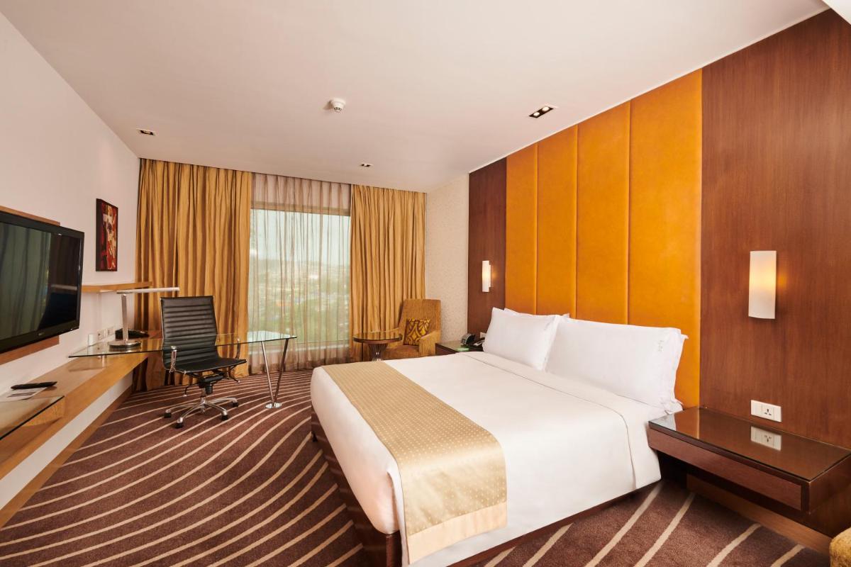a hotel room with a bed and a desk and a television at Holiday Inn Mumbai International Airport by IHG in Mumbai