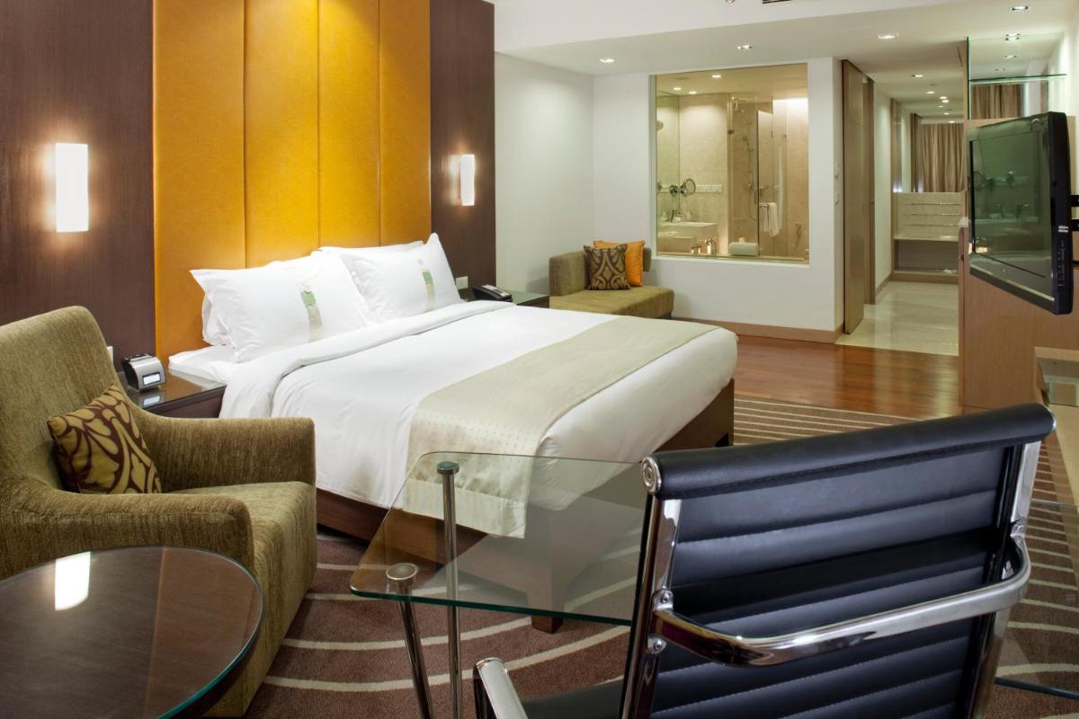a hotel room with a bed and a glass table at Holiday Inn Mumbai International Airport by IHG in Mumbai