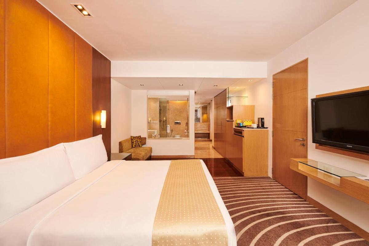 a hotel room with a large bed and a flat screen tv at Holiday Inn Mumbai International Airport by IHG in Mumbai