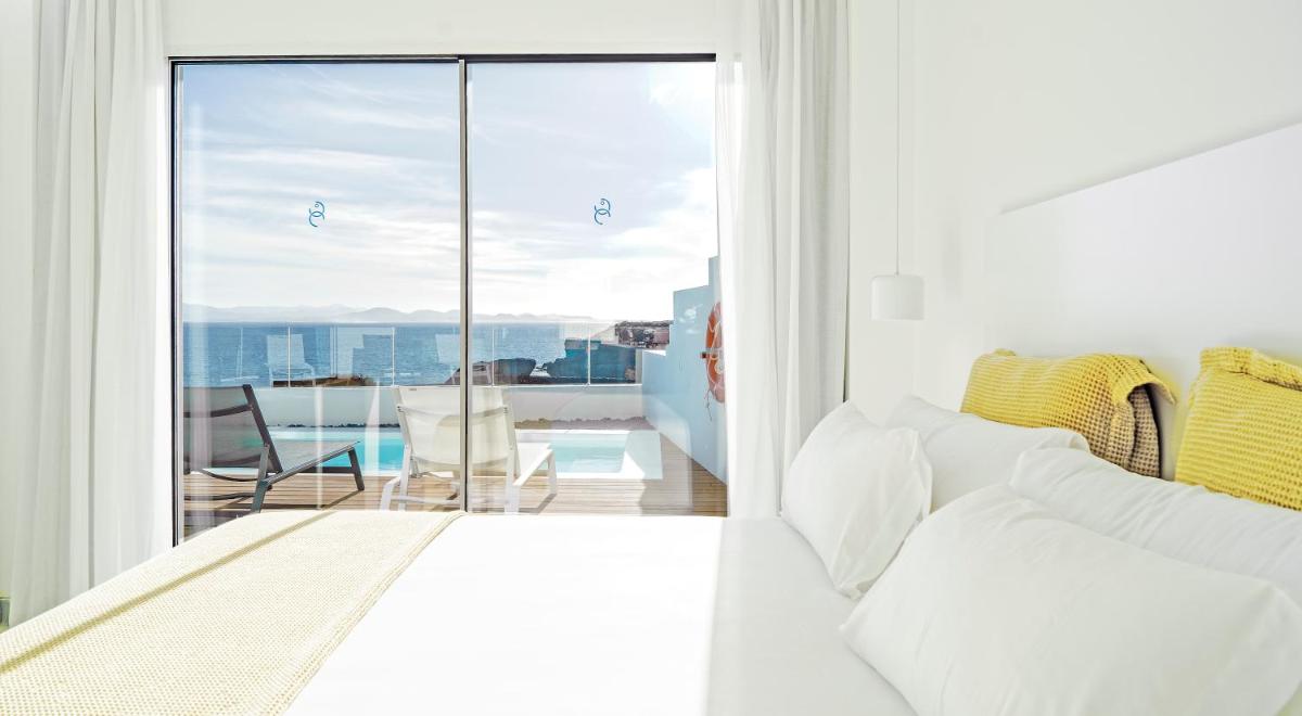 Un dormitorio con una cama y un balcón con vistas. en CalaLanzarote Suites Hotel - Adults Only 16years, en Playa Blanca