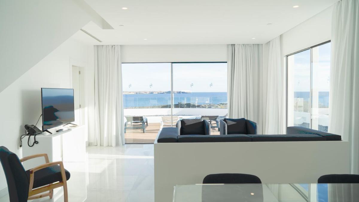 Una sala de estar con un sofá y vista al mar. en CalaLanzarote Suites Hotel - Adults Only 16years, en Playa Blanca