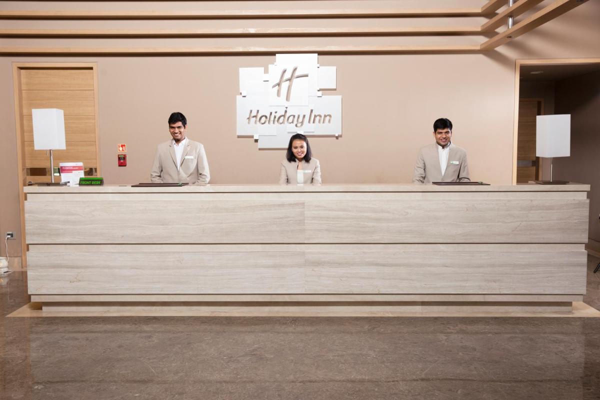 a group of three people standing at a reception desk at Holiday Inn Chennai OMR IT Expressway by IHG in Chennai