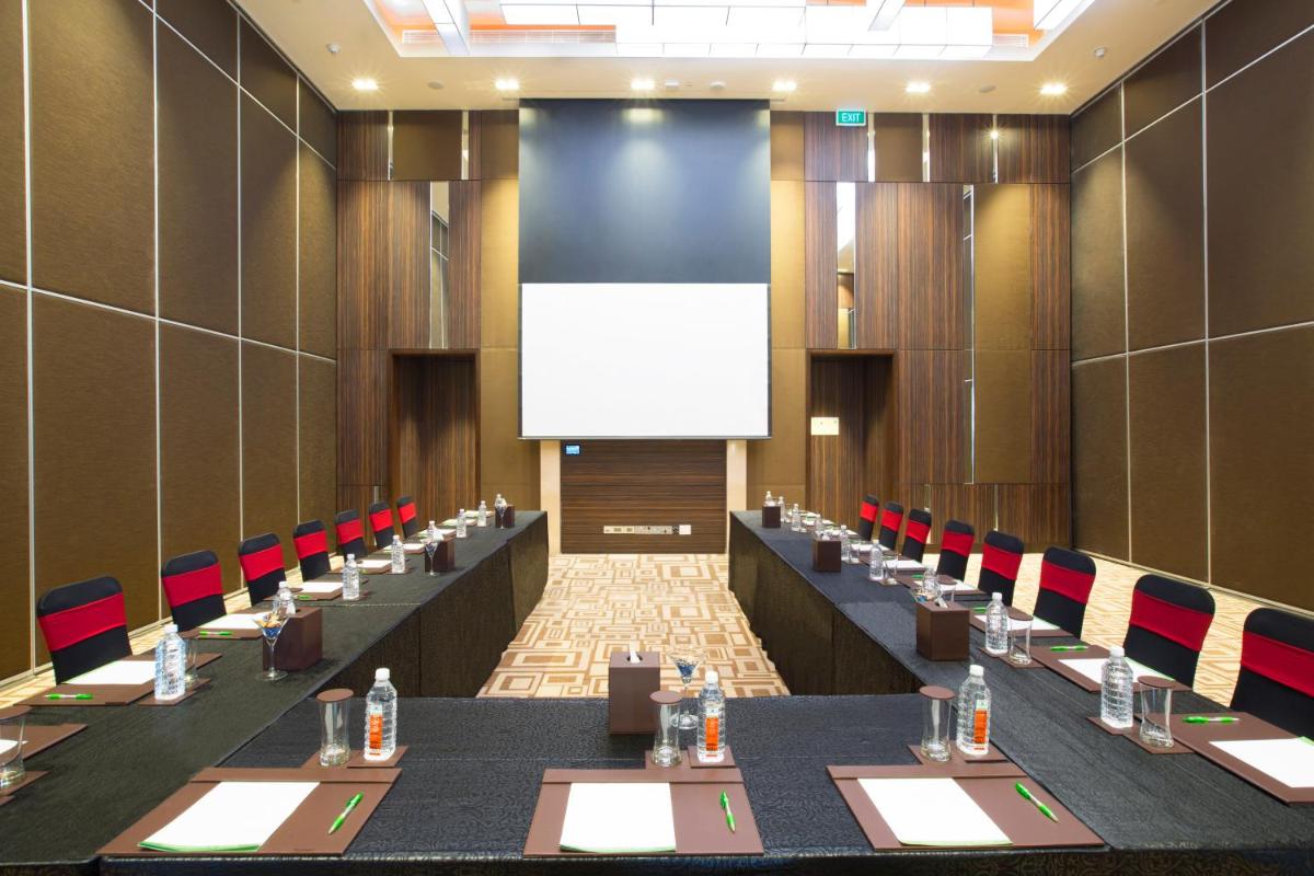 a conference room with long tables and chairs and a screen at Holiday Inn Chennai OMR IT Expressway by IHG in Chennai