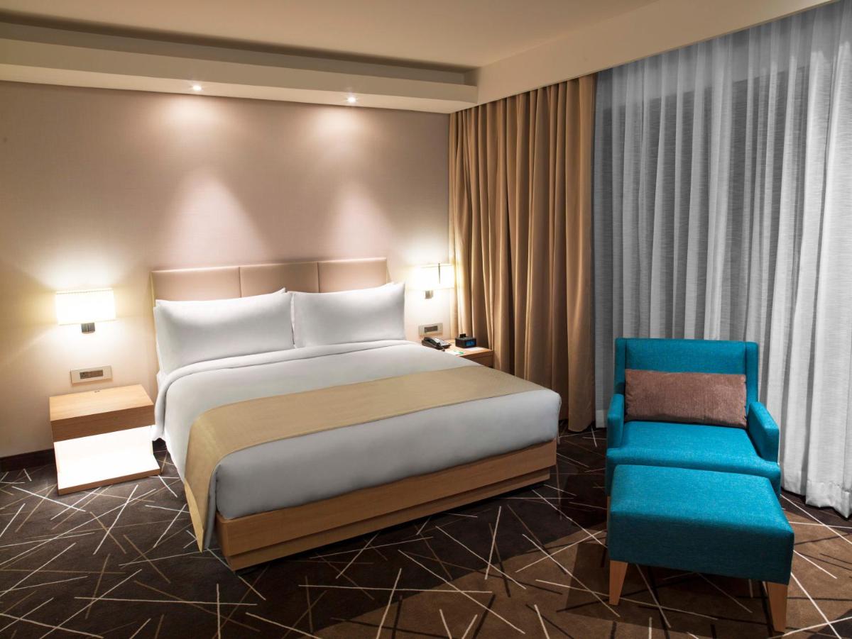 a hotel room with a bed and a blue chair at Holiday Inn Chennai OMR IT Expressway by IHG in Chennai