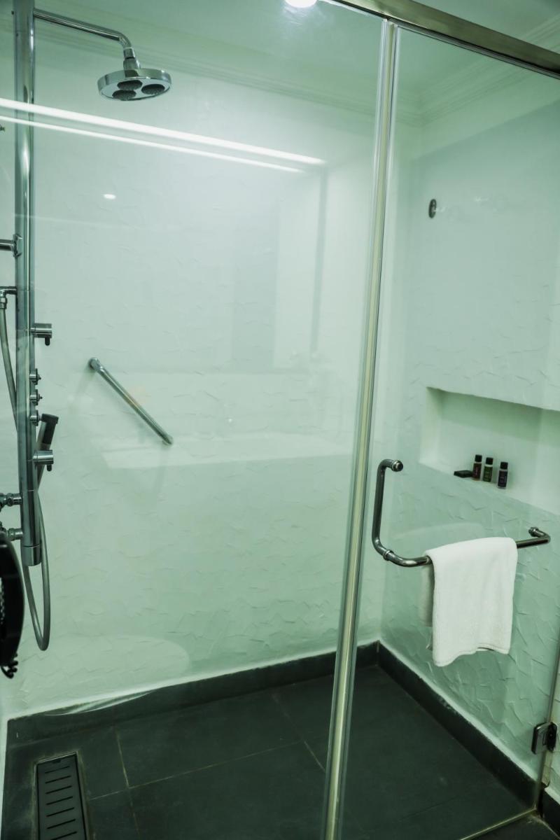 a shower with a glass door with a white towel at Sterlings Mac Hotel in Bengaluru