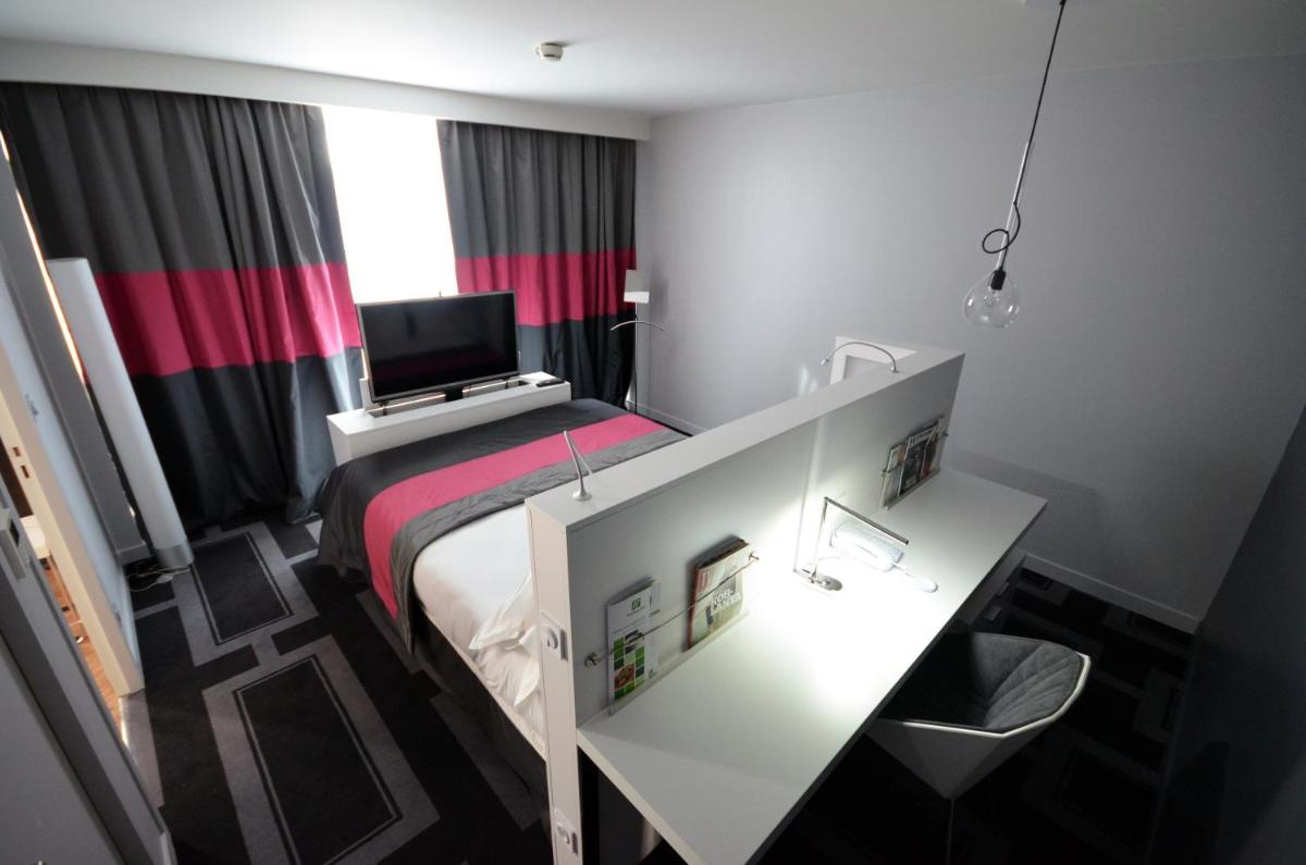 Cette chambre comprend un lit, un bureau et une télévision. dans l'établissement Holiday Inn Dijon Toison D'or by IHG, à Dijon