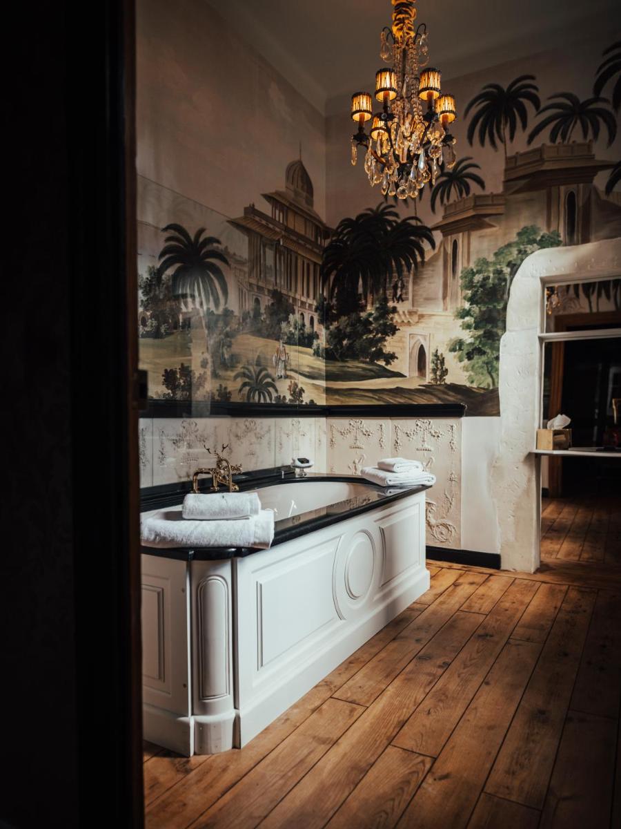 La salle de bains est pourvue d'une baignoire et d'un lustre. dans l'établissement Jardins Secrets, à Nîmes