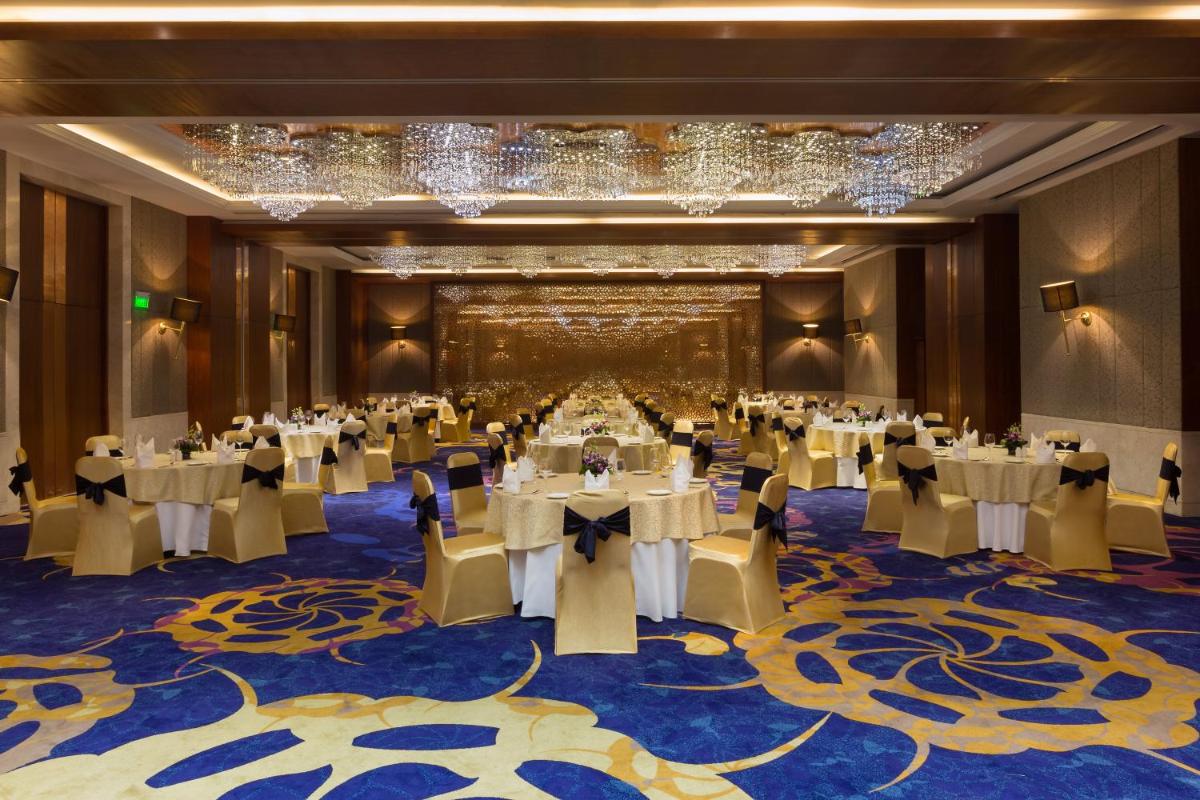 a banquet hall with tables and chairs and chandeliers at Holiday Inn Jaipur City Centre by IHG in Jaipur a banquet hall with tables and chairs and chandeliers at Holiday Inn Jaipur City Centre by IHG in Jaipur