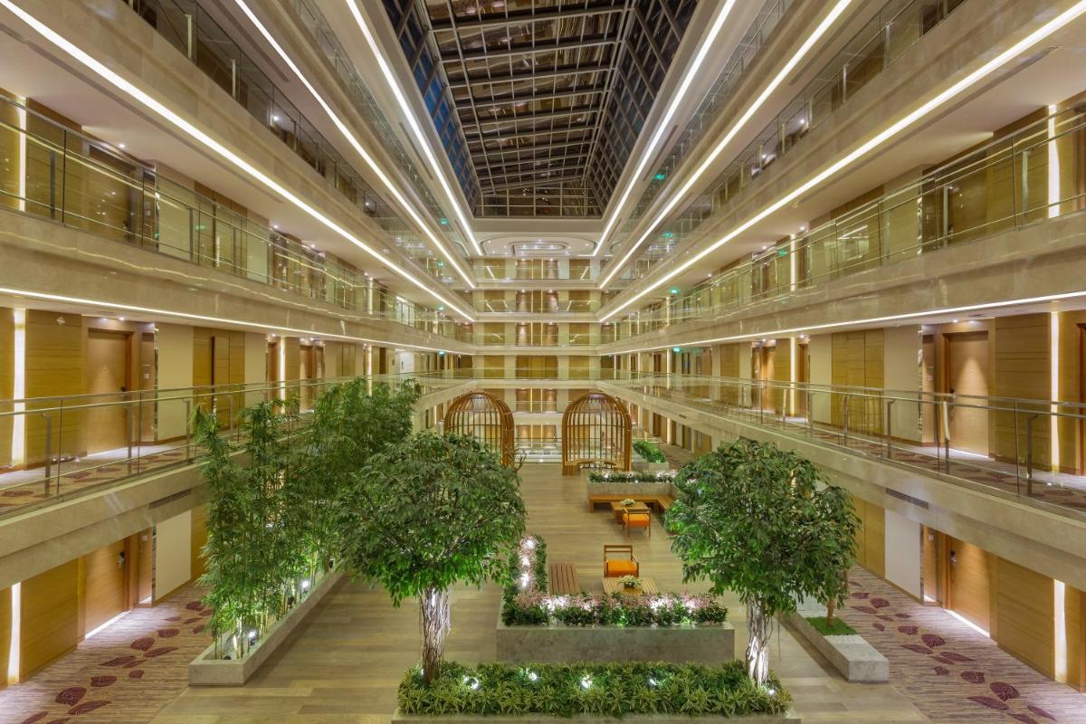 an empty lobby with trees and plants in a building at Holiday Inn Jaipur City Centre by IHG in Jaipur an empty lobby with trees and plants in a building at Holiday Inn Jaipur City Centre by IHG in Jaipur