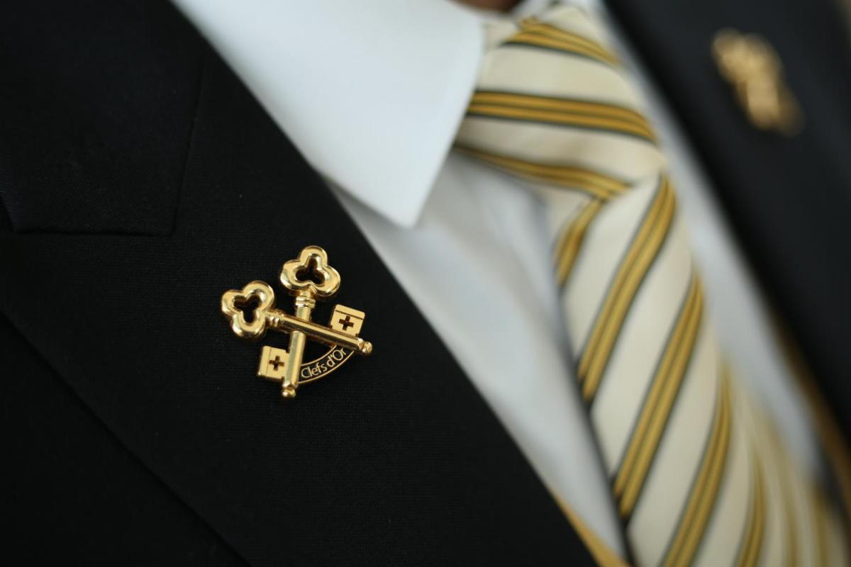 a man wearing a suit with a tie and a gold cross at Taj City Centre Gurugram in Gurgaon
