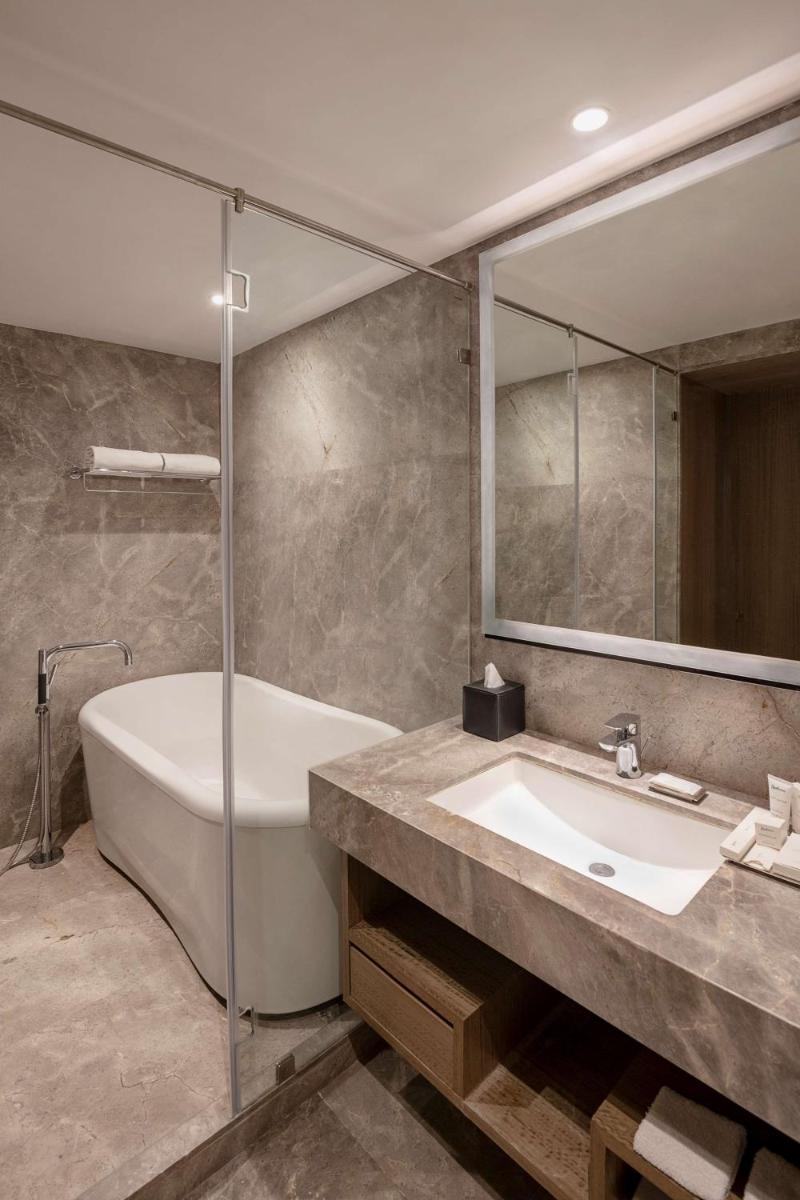 a bathroom with a tub and a sink and a mirror at Radisson Mumbai Andheri MIDC in Mumbai a bathroom with a tub and a sink and a mirror at Radisson Mumbai Andheri MIDC in Mumbai