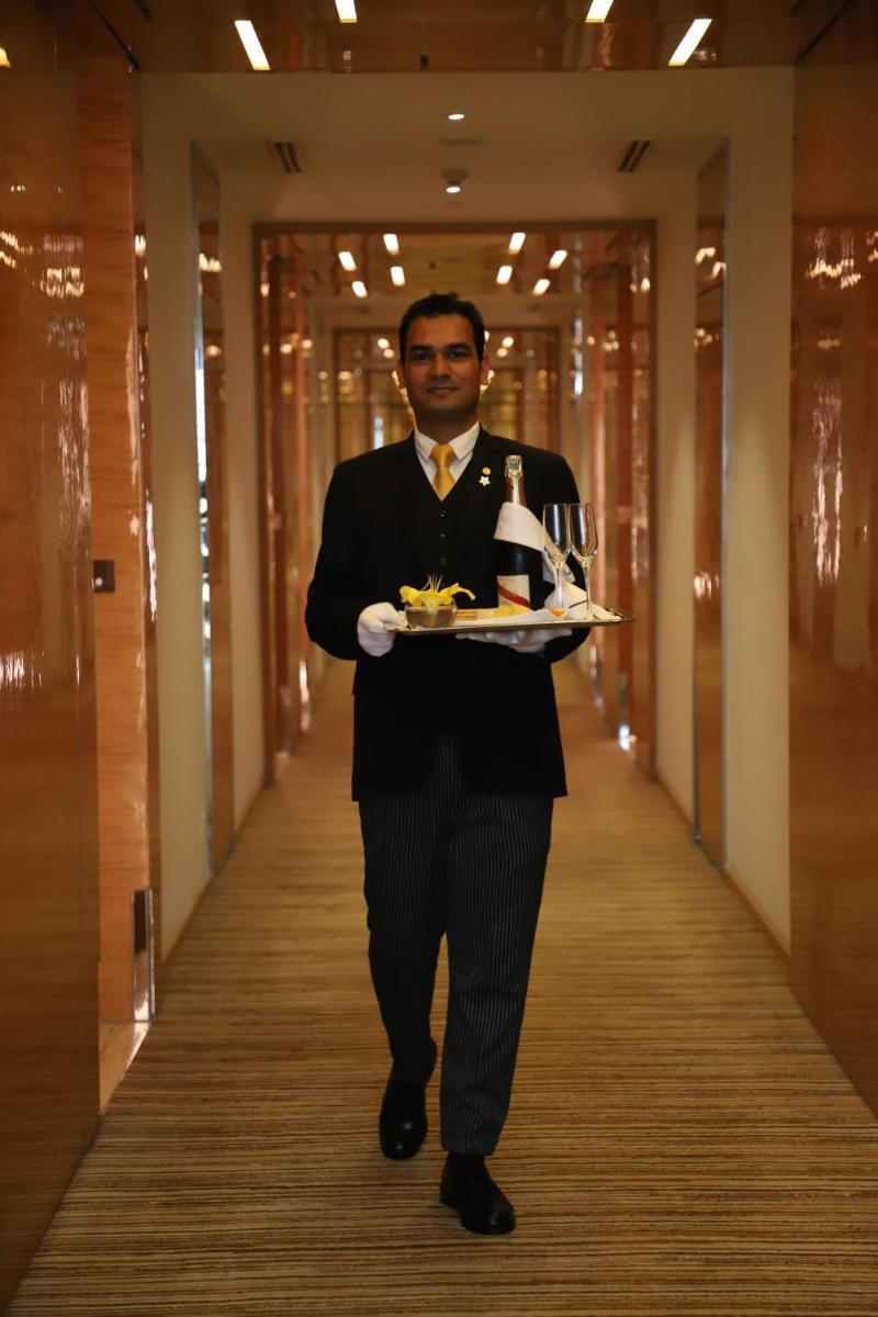 a man in a suit carrying a tray of food at Taj City Centre Gurugram in Gurgaon