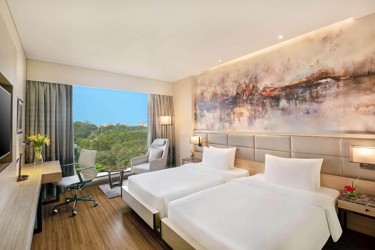 a hotel room with two beds and a large window at Radisson Mumbai Andheri MIDC in Mumbai a hotel room with two beds and a large window at Radisson Mumbai Andheri MIDC in Mumbai