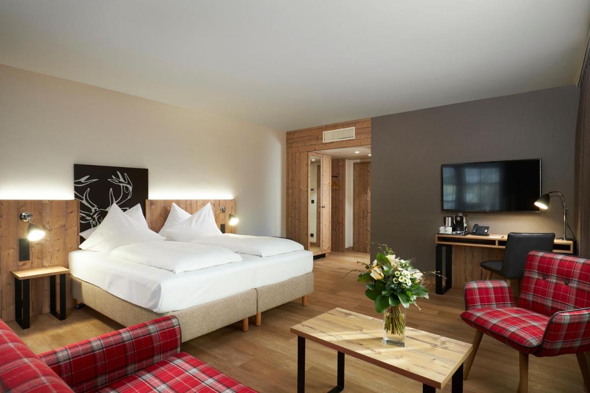 ein Hotelzimmer mit einem Bett und einem Wohnzimmer in der Unterkunft HYPERION Hotel Garmisch - Partenkirchen in Garmisch-Partenkirchen + 37 Fotos