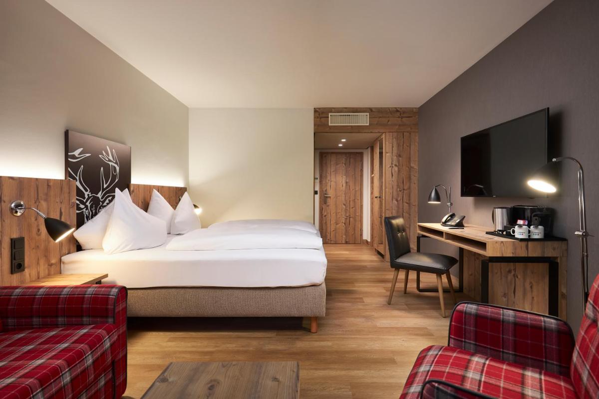 ein Hotelzimmer mit einem Bett und einem Schreibtisch in der Unterkunft HYPERION Hotel Garmisch - Partenkirchen in Garmisch-Partenkirchen