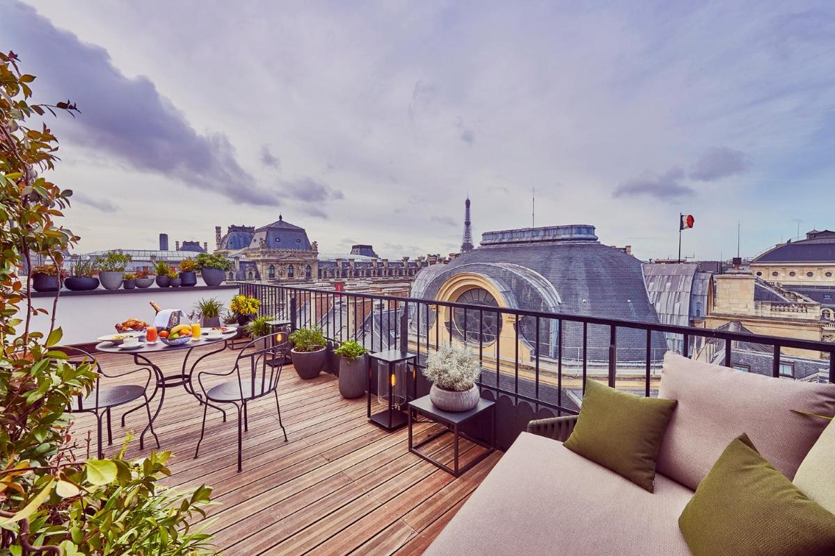 un balcon avec tables et chaises et vue sur la ville dans l'établissement Grand Hôtel Du Palais Royal, à Paris