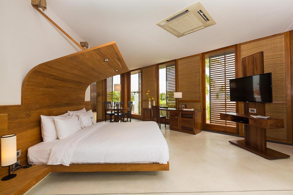 a bedroom with a bed and a flat screen tv at La Villa in Puducherry