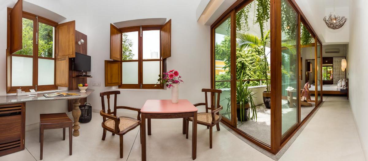 a dining room with a table and chairs and a mirror at La Villa in Puducherry
